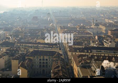 Vista sui tetti del centro storico di Torino dalla parte superiore della Mole Antonelliana in una nebbiosa giornata invernale con comignoli fumanti, Piemonte, Italia Foto Stock