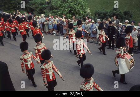 1960s, storico, spettatori che guardano la Guardia della Regina e la banda di marcia al più nobile Ordine del Garter, fuori dal Castello di Windsor, Windsor, Inghilterra, Regno Unito. L'Ordine più nobile del Garter fu fondato dal Re Edoardo III d'Inghilterra nel 1348 ed è l'Ordine più anziano della Knighthood nel sistema degli onori britannici. Foto Stock