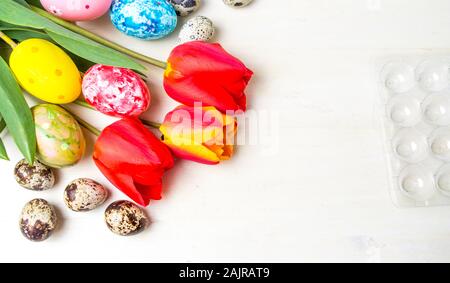 Tulipani rossi e uova di Pasqua sulla tavola di legno Foto Stock