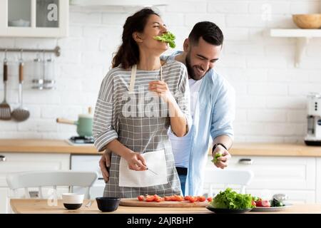 Accoppiare la preparazione di sana insalata vegetariana ridere godendo di processo in cucina Foto Stock