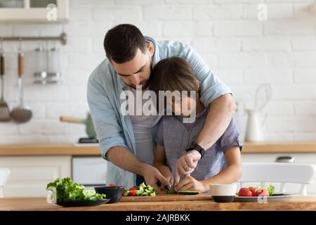 Padre amorevole insegna a suo figlio per cucinare insalata di verdure Foto Stock