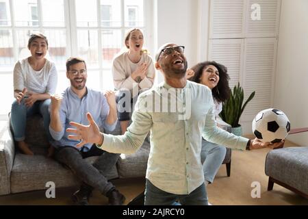 Overjoyed multietnica amici guardare una partita di calcio a casa Foto Stock