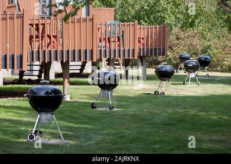 Suburban cortili con lo stesso metallo nero bollitori grill in fila su una giornata d'estate Foto Stock