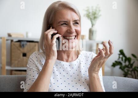 Felice donna matura ridere parlare sullo smartphone a casa Foto Stock