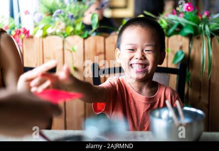 Chinese Boy ricezione tasca rosso sul tavolo da pranzo Foto Stock