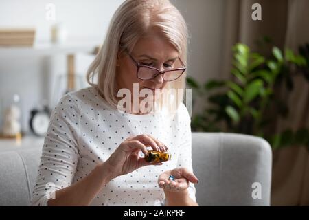 Anziano pensionato femmina aventi farmaci ogni giorno a casa Foto Stock