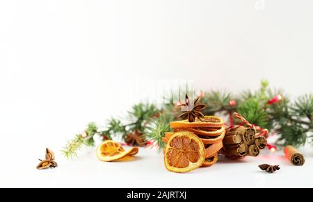 Concetto di Natale. Closeup di composizioni natalizie con fette di arancia essiccate, cannella e anice su sfondo bianco. Foto Stock