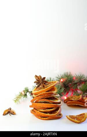 Concetto di Natale. Closeup di composizioni natalizie con fette di arancia essiccate, cannella e anice su sfondo bianco. Foto Stock