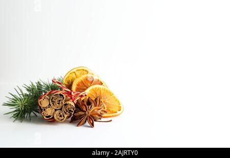 Concetto di Natale. Closeup di composizioni natalizie con fette di arancia essiccate, cannella e anice su sfondo bianco. Foto Stock