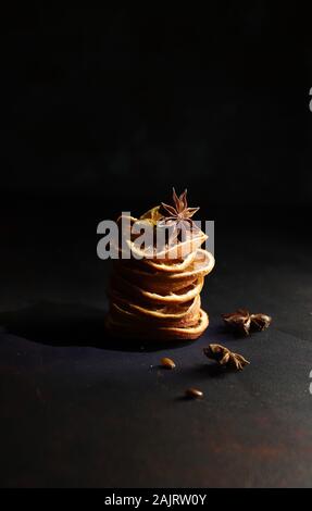 Concetto di Natale. Closeup di composizioni natalizie con fette di arancia essiccate, cannella e anice su sfondo bianco. Foto Stock