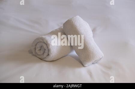 Hotel asciugamani. Bianchi e soffici, laminato asciugamani da bagno e le lenzuola sul letto, camera da letto dettaglio interni. Angolo di Alta Vista. Foto Stock