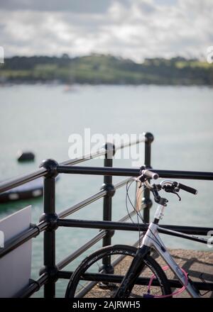 Bicicletta appoggiata contro le ringhiere sulla banchina a Appledore villaggio di pescatori in North Devon, Inghilterra, Regno Unito Foto Stock