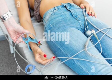 Il dottore attribuisce gli elettrodi dei pioli ECG al paziente polso. Foto Stock
