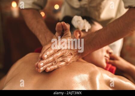 Medicina alternativa. Terapeuta donna di guarigione facendo massaggio ayurvedico con olio a base di erbe di close-up Foto Stock