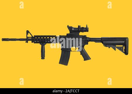 M4 Carbine con vista ottica e un foregrip su sfondo giallo Foto Stock
