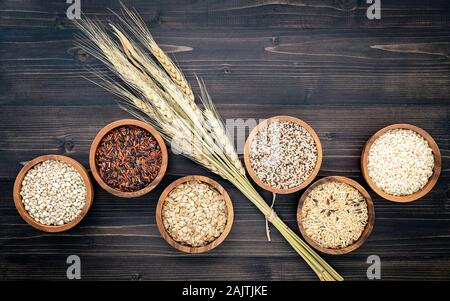 Varie naturale di cereali organici e grani interi seme nella ciotola di legno per un sano ingrediente alimentare prodotto concetto. Foto Stock