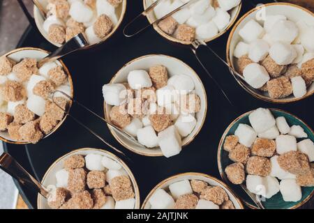 Ciotola con bianco e marrone di cubetti di zucchero e pinze Foto Stock