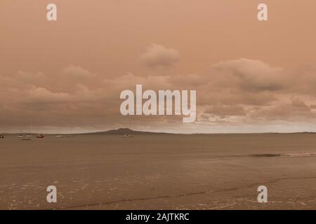 Nuova Zelanda, Isola del Nord - 5 Gennaio 2020: la vista di nebulosità nel cielo da Australia bushfires pende su Torbay spiaggia con Rangitoto island su ba Foto Stock