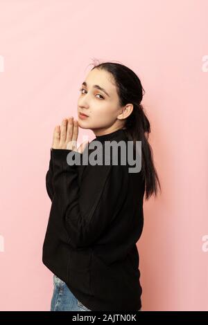 Ritratto di una bella donna di abbigliamento casual che mostra il gesto a mano a mendicare, chiamando per aiutare. Le espressioni del viso del giovane femmina Foto Stock