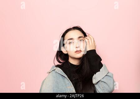 Ritratto di felice medio-orientale ponendo femmina contro un sfondo rosa. Ritratto in studio di un elegante giovane donna. Bellezza e moda Vogue stagionali Foto Stock