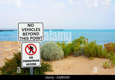 Una foto di 'No i veicoli al di là di questo punto' e 'No accesso pedonale' segni su una spiaggia. Lungo il molo defocalizzata sul retro. Foto Stock