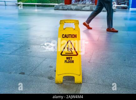 Giallo segnale di avvertimento pavimento bagnato sul pavimento bagnato Foto Stock