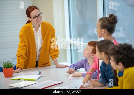 Maestro sorridente lavora con studenti della scuola primaria Foto Stock