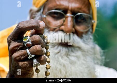 Sadhu pregando e utilizzando la sua mala Foto Stock