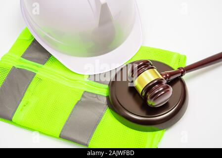 Un lavoro di relativi alla nozione giuridica di sicurezza con cappelli, abiti da lavoro e un giudice martello su uno sfondo bianco. Foto Stock