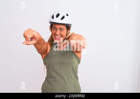 La mezza età coppia ciclista donna che indossa il casco di sicurezza su sfondo isolato rivolti a voi e la fotocamera con le dita, sorridente e positiva allegria Foto Stock