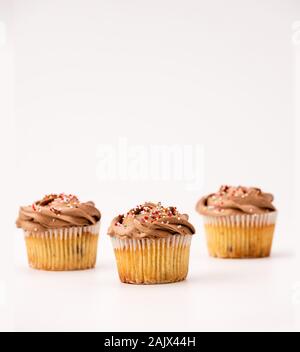 Deliziosi muffin al cioccolato, isolato su sfondo bianco. Pirottini di carta e cibi dolci o non integri in tema di mangiare. Foto Stock