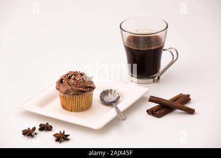 Muffin al cioccolato con calda tazza di caffè, bastoncini di cannella e anice stelle su sfondo bianco Foto Stock