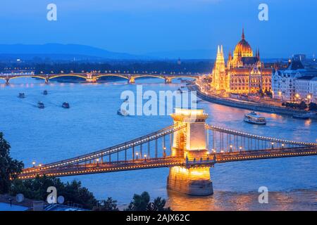 La città di Budapest, Ungheria, le barche turistiche crociera sul fiume Danubio lungo il ponte delle catene e il palazzo del Parlamento su una serata blu Foto Stock