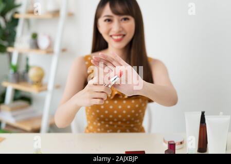 Che cosa è questo. Piuttosto giovane donna seduta nella parte anteriore della fotocamera durante la sperimentazione dei cosmetici Foto Stock