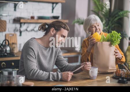 Grey-haired mom e suo figlio a discutere di shopping Foto Stock