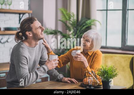 Grey-haired mom e suo figlio avente caffè insieme Foto Stock