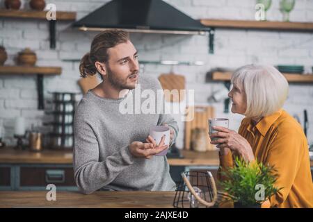Grey-haired mom e suo figlio avente un caffè la mattina Foto Stock