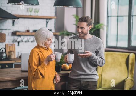 Giovane uomo bello in camicia grigia e la sua mamma a discutere di qualcosa Foto Stock