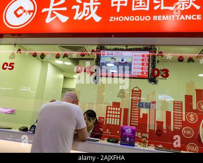 CHINATOWN, Singapore - 26 dic 2019 - Vista del uomo cinese presso il bancone di un trasferimento di denaro azienda specializzata nella cessione di denaro da Singapore Foto Stock