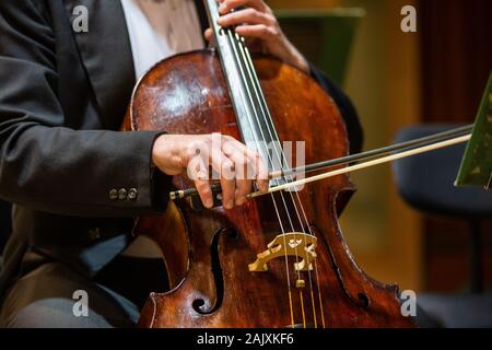 Orchestra Sinfonica di esibirsi sul palco e riproduzione di un concerto di musica classica, il violoncellista in primo piano Foto Stock