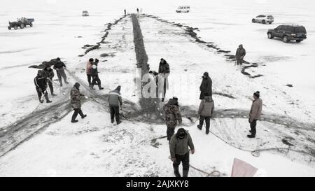 Lavoratori cinesi tirare una gigantesca rete da pesca di aspettarsi un buon raccolto sulla congelati Wolong lago nella contea di Kangping, Shenyang City, a nord-est della Cina di Liaon Foto Stock