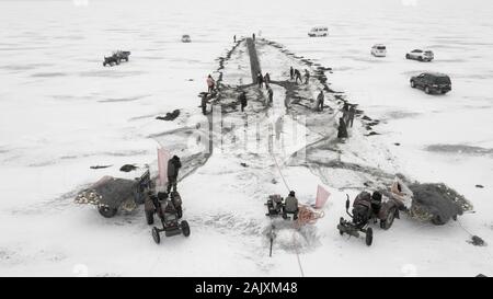 Lavoratori cinesi tirare una gigantesca rete da pesca di aspettarsi un buon raccolto sulla congelati Wolong lago nella contea di Kangping, Shenyang City, a nord-est della Cina di Liaon Foto Stock