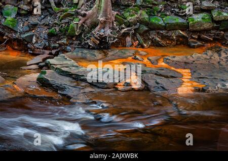 Pietra arenaria nel letto del fiume Don, con acqua che scorre rapidamente attraverso antichi boschi, e l'ocra trafilare dalle vicine giacche di carbone Foto Stock