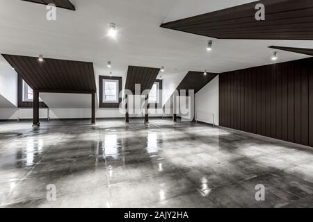 Vuoto non ammobiliato loft mansarda sala interna con colonne di legno e calcestruzzo bagnato pavimento sul livello del tetto in nero e stile whote colore Foto Stock