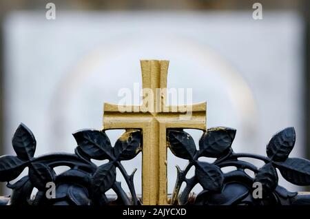 Golden cross su una tomba in un cimitero Foto Stock