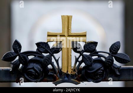 Golden cross su una tomba in un cimitero Foto Stock