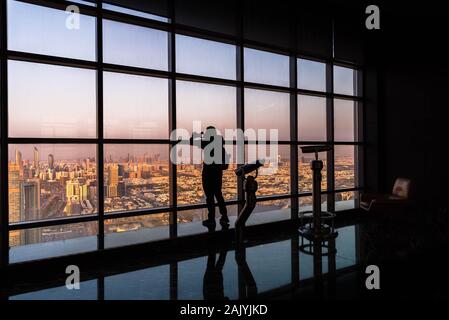 Abu Dhabi: Silhouette di turista di scattare una foto con lo smartphone dal ponte di osservazione a 300, Etihad towers, torre di spettatori (binocolo) e sullo skyline Foto Stock