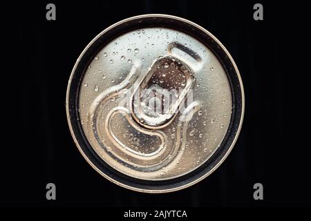 Metallo lucido cola può coperchio con gocce di acqua su sfondo nero. Golden Bottiglia di bevanda, coperchio della confezione di birra. Vista superiore Foto Stock