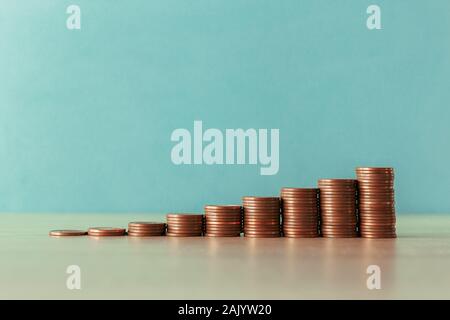 Foto di stock di una scala ascendente di monete su uno sfondo blu Foto Stock