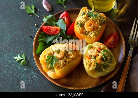 Piatto vegetariano. Peperoni ripieni di quinoa, i gamberetti e le verdure su pietra scura tabella. Foto Stock